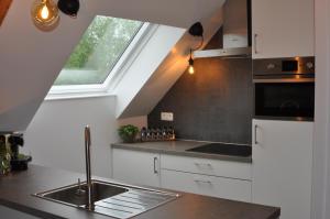 a kitchen with white cabinets and a sink and a window at Casa-Anja in Zingem