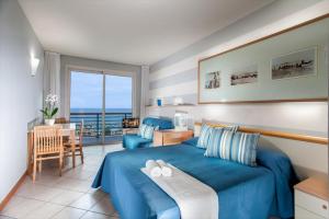 een slaapkamer met een blauw bed en een tafel en stoelen bij Hotel Valverde & Residenza in Cesenatico