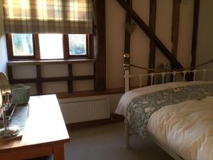 a bedroom with a bed and two windows at Heartwood Barn in Ticehurst