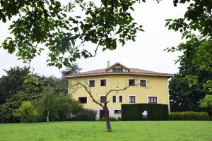 a large yellow house in a green field at Hotel Hontoria in Hontoria