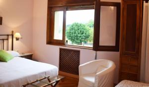 a bedroom with a bed and a chair and a window at Hotel Hontoria in Hontoria
