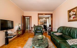 Il comprend un salon doté d'un mobilier en cuir vert et d'une télévision à écran plat. dans l'établissement Apartment Savin, à Herceg-Novi