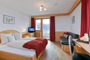 ein Hotelzimmer mit einem Bett, einem Schreibtisch und einem Fernseher in der Unterkunft Apart Faldershof in Fiss