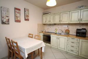 a kitchen with white cabinets and a table and a sink at Vila Golful Dunării in Dubova