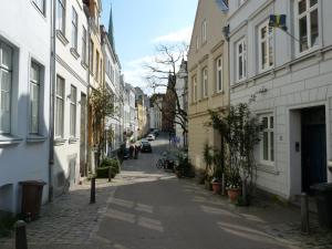 a narrow alley with buildings and a street with cars at Ferienwohnung zum Burgtor in Lübeck