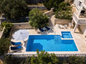 einen Blick über einen Pool mit Stühlen und einem Sonnenschirm in der Unterkunft Villa Matic in Vela Luka