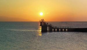 a dock in the ocean with the sun setting at Seashore Lodge Guesthouse in Galway
