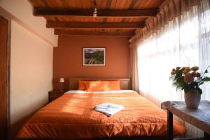 una camera da letto con un letto con lenzuola arancioni e una finestra di Tambo Cusco Inn a Cuzco Altre 20 foto