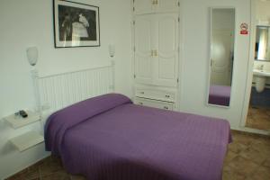 1 dormitorio con cama morada y espejo en El Rincón de Isabel, en Conil de la Frontera