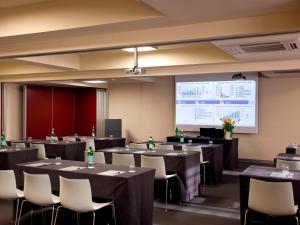 une salle de conférence avec des tables et des chaises et un écran de projection dans l'établissement Hotel Zone, à Rome