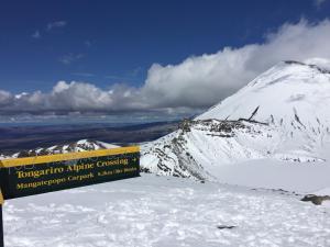 un cartel en la cima de una montaña cubierta de nieve en Tongariro Crossing Lodge, en National Park