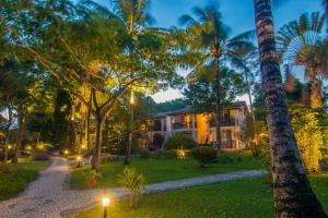 a house in the middle of a yard with palm trees at Manacá Pousada Parque in Arraial d'Ajuda
