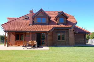 a wooden house with a table and chairs in front of it at Dom wakacyjny z basenem in Dębki