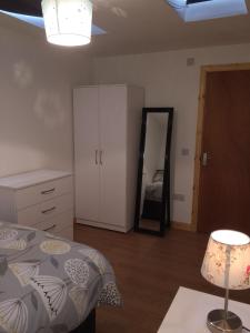 Schlafzimmer mit einem Bett, einer Kommode und einem Spiegel in der Unterkunft Millburn Apartments in Inverness