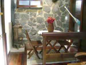 a table with a vase with flowers on it next to a stone wall at Chalé charmoso e aconchegante em Visconde de Maua in Visconde De Maua