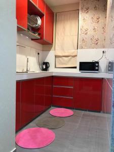 a kitchen with red cabinets and pink mats on the floor at Rumah Cik Ani in Shah Alam