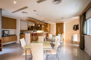 cocina y comedor con mesas y sillas blancas en Uline Motel, en Taipéi