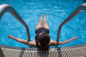 a woman laying in the water in a swimming pool at Bossotel Chiang Mai - SHA Plus in Chiang Mai