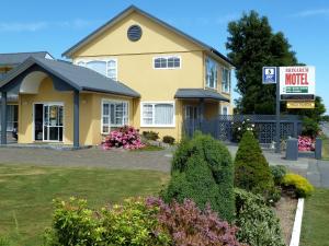 a yellow house with a sign in front of it at Monarch Motel in Invercargill