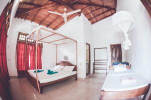 a bedroom with two beds and a ceiling fan at Rupa's Hotel in Arugam Bay