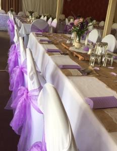 une rangée de tables avec un chiffon de table violet et blanc dans l'établissement Caves Motor Inn, à Te Kuiti