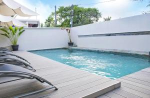 a swimming pool with chairs on a wooden deck at Beachcove Apartment 3 in Pereybere