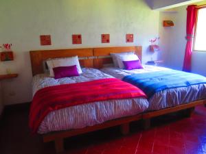 1 dormitorio con 2 camas con mantas y almohadas coloridas en Hotel Molino Machu Picchu Peru, en Ollantaytambo