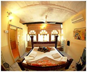 
a room with a bed, a table, and a window at The Blue House in Jodhpur
