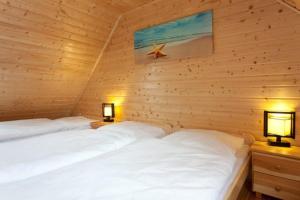 two beds in a wooden room with two lamps at Domki Marlin in Rewal