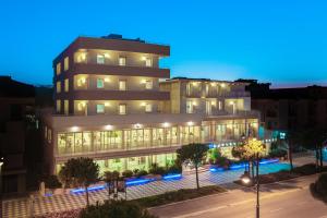 un bâtiment éclairé dans une ville la nuit dans l'établissement Hotel Nettuno, à Cesenatico