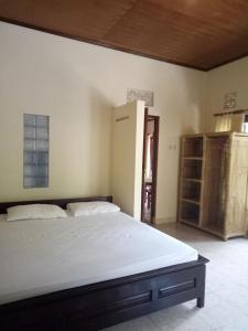 a bedroom with a white bed and a closet at Mimba Private House in Padangbai