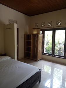 a bedroom with a bed and a large window at Mimba Private House in Padangbai