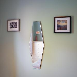 a mirror on a white wall with two pictures at Conwy Cottage in Conwy
