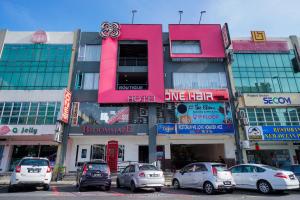 a pink building with cars parked in a parking lot at Bloommaze Boutique Hotel Puchong in Puchong