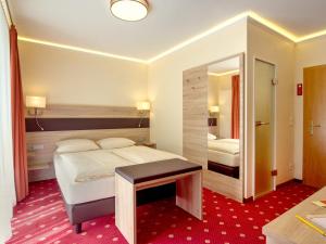 una camera d'albergo con letto e specchio di Hotel Kriemhild am Hirschgarten a Monaco