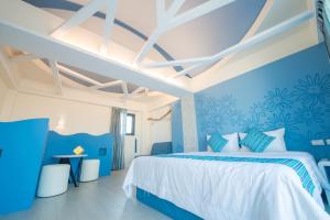 Sapphire Inn في ماغونغ: غرفة نوم زرقاء وبيضاء مع سرير