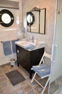 ein Badezimmer mit einem Waschbecken, einem Spiegel und einem Stuhl in der Unterkunft L ' Authentique in Pernes-lès-Boulogne