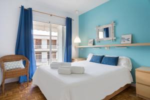 a bedroom with a large bed with blue walls and a window at Stay U-nique Apartments Sitges Beach in Sitges