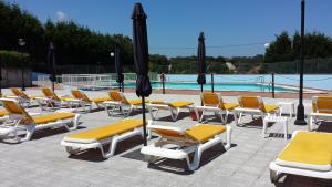 a group of lounge chairs and umbrellas next to a pool at Hotel Campomar in Isla