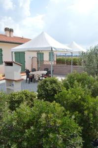 un patio con una tienda blanca, una mesa y sillas en Agriturismo OlivoMare, en Piombino
