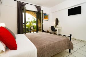 a bedroom with a bed with a red pillow and a television at Olympia Zervea Studios with Pool - Apartment in Kardamili
