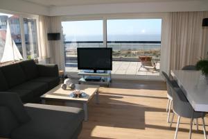 a living room with a couch and a tv and a balcony at Penthouse Poseidon in Blankenberge