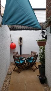 a patio with a table and chairs and a blue umbrella at Chinwin Cottage in Weymouth