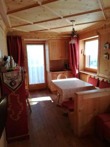 a room with a table and red chairs in a cabin at Appartamento Gliera in Arabba