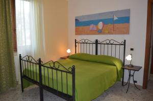 ピオンビーノにあるAgriturismo OlivoMareの緑のベッドと壁に絵画が飾られたベッドルーム1室
