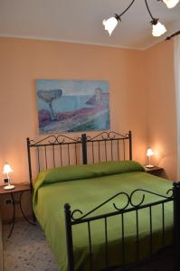 Un dormitorio con una cama verde con una pintura en la pared en Agriturismo OlivoMare, en Piombino