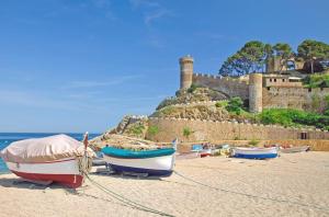 trzy łodzie na plaży z zamkiem w tle w obiekcie Apartment Tossa w Tossa de Mar