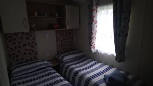 two beds in a small room with a window at Bude Caravan Caromax - Families and Couples Only in Bude +21 photos