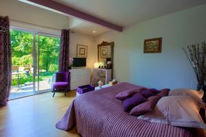 una camera da letto con un grande letto con cuscini viola di B&B La Closerie 33 a Sadirac