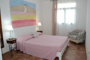 um quarto com uma cama rosa e uma cadeira em Agriturismo OlivoMare em Piombino